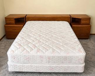 gn- This queen size bed comes complete with a comfortable mattress and a distinctive headboard designed in three separate wooden pieces. The headboard features integrated storage compartments, including drawers and a top lift-up section, providing practical and stylish storage solutions. Crafted from warm-toned wood, the furniture set includes matching nightstands with multiple drawers, enhancing the overall functionality and aesthetic of the bedroom setup.