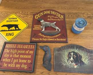 lc- This Dog Lover Collection features a charming assortment of decorative items perfect for canine enthusiasts. It includes a vintage-style 'Gun Dog Tavern' sign with a detailed German Shorthaired Pointer figurine and welcoming text, a bright yellow 'German Shorthaired Xing' caution sign, a framed motivational plaque titled 'Simple Pleasures' emphasizing the joy of being with your dog, and a rustic cast iron dog figurine. Highlighting a rich color palette of warm reds, yellows, and natural cast iron tones, these items vary in size and material, making a perfect blend of rustic and classic dog-themed decor.