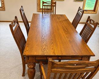 cy- This elegant solid oak dining table set includes six matching chairs, perfect for family meals and gatherings. The table measures 29 inches in height, 82 inches in length, and 39.5 inches in width, providing a spacious surface for dining. Unique to this set, the table features two built-in drawers located at each end, ideal for storing utensils or dining essentials. Crafted from durable oak wood, the table and chairs showcase a warm, natural finish with intricately turned legs and comfortable woven seat cushions on the chairs, blending classic design with functional storage.