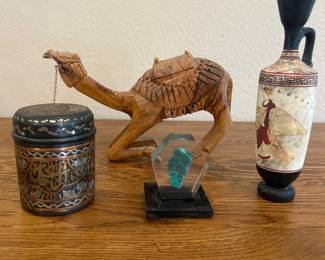 ko- This finely crafted wooden camel figurine features detailed hand-carved patterns depicting a traditional saddle and decorative elements. Measuring approximately 11 inches in length and 8 inches in height, the figurine showcases a natural wood finish that highlights the texture and grain. This piece is an exquisite example of Indian handcrafted decor, perfect for adding a touch of rustic charm and cultural elegance to any space. Also there are a few random pieces with an India theme.