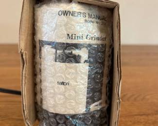 jg- This Salton Mini Grinder features a compact and portable design, perfect for small grinding tasks. The unit is securely wrapped in bubble wrap and packaged in its original cardboard box for protection. It measures approximately 7.5 inches tall, making it easy to store and handle. The grinder comes with an owner's manual to assist in setup and operation. Its sturdy black exterior is made of durable material, ensuring reliable performance. Ideal for anyone needing a small, efficient electric grinder.