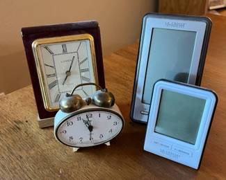 me- This collection features four distinctive desktop clocks, blending vintage charm with modern technology. Included is a classic Linden clock with a rich mahogany wooden frame, gold trim, and an elegant white face with Roman numerals, perfect for a traditional decor. A vintage twin-bell alarm clock with an oval white face and brass finish adds nostalgic appeal. The set also includes two sleek digital clocks by La Crosse Technology, showcasing compact sizes and minimalist designs with black and white casings, equipped with intuitive buttons for easy time setting. This assortment highlights a variety of materials including wood, metal, and plastic, providing versatility and style for any desk or bedside table.