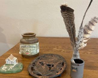 kx- This unique assortment of collectables includes a variety of vintage and decorative items, each with distinct character and charm. Highlights include a brown stoneware jar labeled 'moutarde à l'ancienne,' a small blue ceramic toothpick holder marked 'Prattville AL,' a miniature ceramic model of Lincolnhire Hall on a green base, and an intricately carved, oval-shaped floral metal trivet. The pieces vary in material and style, showcasing rustic pottery and detailed craftsmanship, ideal for collectors or as decorative accents.