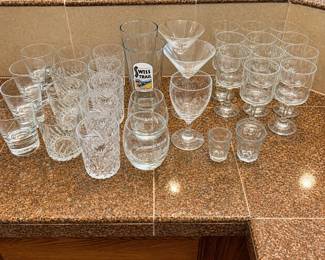 lg- This collection features a diverse assortment of 33 bar style glasses, ideal for any home bar or entertaining setting. The set includes various glass types such as highball, cocktail, whiskey, shot, and stemmed glasses, each exhibiting clear glass construction with some featuring intricate cut designs. Perfect for serving a wide range of beverages, this assortment emphasizes versatility and classic barware aesthetics. The glasses vary in size and shape, providing options for different drink preferences and occasions.