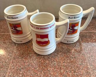 lm- This set includes three ceramic beer steins, each standing 6 inches tall with a diameter of 3.5 inches. The steins feature colorful historic insignias from Fort Carson, Colorado, including unit crests and emblems for Delta Demons and Company C, 4th Engineer Battalion. Crafted from durable ceramic, these collectible steins showcase detailed artwork in red, yellow, and white hues, perfect for military memorabilia enthusiasts or collectors of vintage drinkware.