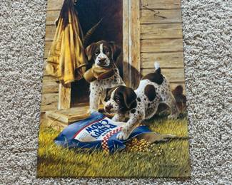 du- This metal wall art, created by artist Lynn R. Kaatz in 1997, showcases two playful spotted puppies interacting with a spilled bag of 'Puppy Chow' dog food outside a rustic wooden shed. The piece highlights vivid earthy tones with detailed grass textures and lifelike puppy expressions, evoking a warm, nostalgic country vibe. Produced by Main Street Land Company, Inc., and made in the USA, the artwork measures approximately standard wall art size, crafted on sturdy metal with pre-drilled holes for easy hanging. Perfect for dog lovers and collectors of vintage Americana decor.