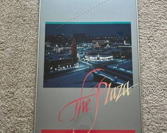 dx- Vintage framed poster titled “The Plaza”, depicting the Country Club Plaza in Kansas City, Missouri illuminated for the holiday season. The lower text reads, “The Plaza. Very much in the heart of Kansas City, Missouri.” The image shows the Plaza’s distinctive Spanish-inspired architecture, tower, storefronts and extensive holiday lighting. Presented in a slim silver-tone metal frame under glass. A label on the reverse identifies custom framing by The Frame Maker, Westloop Center, Manhattan, Kansas. Appears to be a promotional or decorative poster rather than an original fine-art print. No artist signature or edition number is visible in the photographs provided. Condition appears good overall with light age and display wear; please review photos for exact condition.