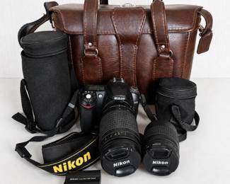 as- Nikon D50 digital SLR camera bundle with two Nikon AF Nikkor zoom lenses and multiple carrying cases. Includes: ● Nikon D50 DSLR camera body ● Nikon AF Nikkor 70-300mm f/4-5.6G zoom lens ● Nikon AF Nikkor 28-80mm f/3.3-5.6G zoom lens ● Nikon Li-ion battery pack ● Nikon neck strap ● Brown camera/equipment bag ● Two black padded lens/accessory cases ● Nikon lens caps as shown Camera and lenses show normal signs of previous use. The lenses appear visually clean from the exterior; please review photos closely for overall condition. Battery is included, but no battery charger is present, so the camera could not be tested. Camera and lenses are therefore being sold as-is with functionality unknown. Believed to be working per previous owner.