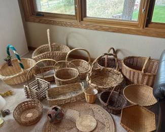 gb- This unique Wicker Collection features a diverse assortment of handwoven baskets and decorative items crafted from natural wicker materials. The collection includes various basket shapes such as picnic baskets, round and rectangular trays, and a rustic twig basket, each showcasing intricate weaving techniques. Highlighted by natural brown and beige tones with occasional accents of red and black, these pieces vary in size from small decorative items to larger, functional baskets with handles, perfect for storage, display, or home decor.