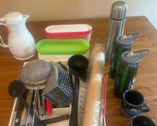 kl- This assorted kitchen essentials set features a variety of practical and useful items perfect for everyday kitchen needs. Included is a white pitcher with an orange lid measuring approximately 9 inches tall, ideal for serving beverages. The set also includes a stainless steel thermos standing about 11.5 inches high, useful for keeping drinks hot or cold. There are two colorful storage containers with red and green lids, measuring around 11.5 inches in length, excellent for food storage. Additional kitchen tools such as graters, measuring spoons, and utensils accompany the set, enhancing its versatility. Crafted from durable materials including plastic and stainless steel, this collection brings a blend of function and vibrant color to your kitchen workspace.
