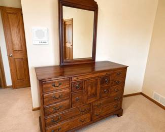 hc- Quality Lexington Furniture dresser with matching mirror from The World of Bob Timberlake collection. Features a warm cherry-toned wood finish, numerous drawers in varying sizes, a central paneled cabinet, traditional dark metal hardware, and a large matching framed mirror with decorative shaped crest. Includes two original-style keys and Bob Timberlake/Lexington Furniture tag as shown. A substantial, well-made piece with abundant storage and classic traditional styling. Appears to be in very good overall pre-owned condition with light wear consistent with normal use. Please review photos for details and condition.