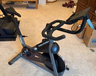 il- This Pro-Form Sport CX indoor exercise bike features a sleek, modern design with a sturdy black and gray frame. It includes an adjustable digital console for tracking your workout metrics and a red resistance knob for easy intensity adjustments. The bike is compact and suitable for home use, equipped with multi-position handlebars and a comfortable seat. The durable steel construction ensures long-lasting performance, making it a perfect addition for cardio workouts in any home gym setting.