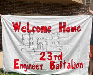 cc- This large white fabric banner (65in x 95in) features bold red lettering that reads 'Welcome Home 23rd Engineer Battalion' with an outlined sketch of a historic castle at the center. The banner is designed to celebrate and honor the 23rd Engineer Battalion with a welcoming message. It is lightweight and suitable for outdoor use, ideal for display during homecoming events. Included separately is the United States Army emblem print on 10 cards (6in x 4.5in) with envelopes included, sealed in protective packaging, which adds a distinguished and patriotic touch to the set.