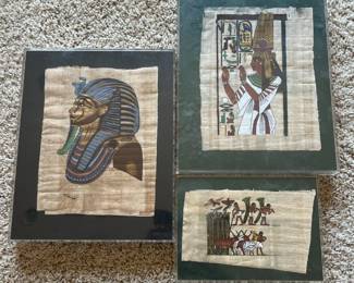 em- This set includes three framed Egyptian papyrus artworks, each showcasing intricate depictions of ancient Egyptian culture. The artworks feature a detailed profile of a Pharaoh wearing traditional blue and gold headdress, a regal figure in white robes with a tall headdress surrounded by hieroglyphics, and a vibrant scene of figures and animals in traditional attire. Each piece is mounted on authentic papyrus, highlighting the natural beige tones and textured surface of the material. The frames have a dark green matte border, enhancing the vivid colors of the hand-painted illustrations. These artworks vary in size but collectively offer a compelling glimpse into ancient Egyptian artistry and history, perfect for collectors or enthusiasts of historical and cultural decor. Large Frames: 10in x 8in Small Frame: 5.3in x 7.3in