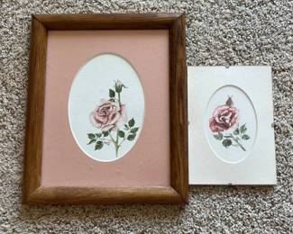 er- This set features two delicate hand-painted watercolor illustrations of roses, each framed individually. One piece showcases a pink rose with rich green leaves set against a soft pink mat, enclosed in a warm-toned wooden frame. The second painting, displaying a rose with subtle red and pink hues, is mounted on a cream-colored mat board. Both artworks are signed and dated by the artist 'Rogers' in 1990 and 1991, adding a personal touch. The frames highlight the natural wood grain, complementing the floral artistry and making these pieces perfect for adding a classic botanical accent to any room. Large Frame: 11.5in x 9.5in Smaller Frame: 7in x 5in