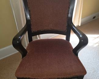 traditional dark wood armchair features a curved wooden frame and reddish-textured upholstered seating and back panel.