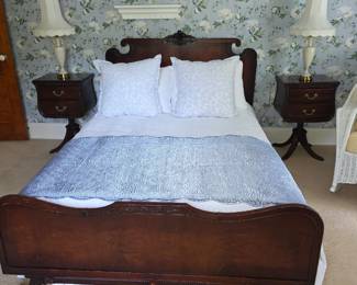 classic dark wood antique sleigh bed paired with matching mid-century nightstands and a blue floral wallpaper backdrop.    