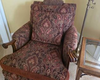 This traditional burgundy paisley upholstered armchair features carved wood trim and a