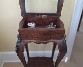  antique wooden lift-top work table or sewing stand features a glass-paneled display lid, curved cabriole legs with decorative bronze-tone mounts, and a lower open shelf.