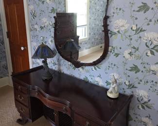 dark wood vintage vanity and matching wall mirror feature classic mid-20th-century serpentine drawer fronts and ornate scroll carvings.    