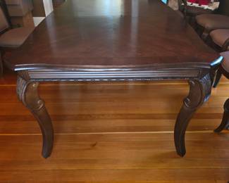 traditional mahogany extension dining table features an elegant chevron-patterned wood veneer top and ornate, carved cabriole legs