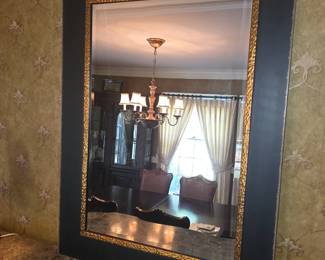                     This large rectangular wall mirror features a wide matte black outer frame accented with an ornate, embossed gold-gilt inner trim.
