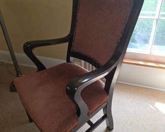 traditional dark wood armchair features a curved wooden frame and reddish-textured upholstered seating and back panel.