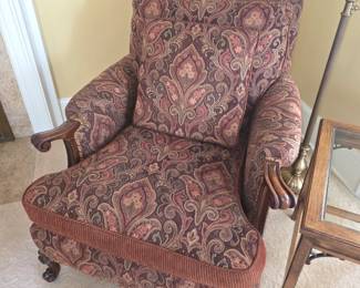 This traditional burgundy paisley upholstered armchair features carved wood trim and a