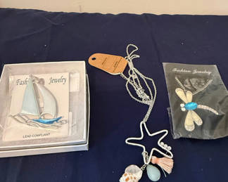 Lot 203: Assorted fashion jewelry: sailboat pendant, dragonfly brooch, and shell charms