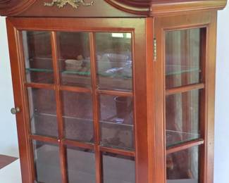 Bombay Company wall curio cabinet with a cherry wood finish and glass shelves