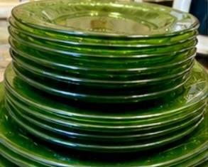 green Depression-era and pressed glass, including plates, bowls, cups and saucers, serving platters, snack dishes, and more. Features a lovely mix of floral, swirl, and geometric patterns, with additional colorful vintage glassware displayed alongside.
