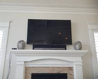 TV with bracket; sound bar. Fireplace mantel; fireplace insert