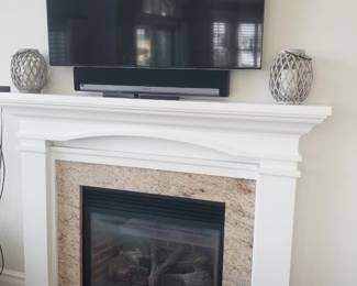 TV with bracket; sound bar. Fireplace mantel; fireplace insert