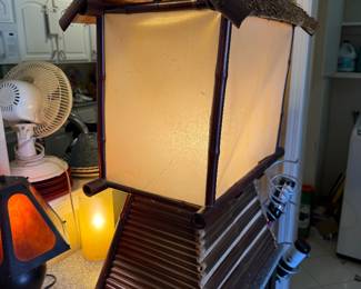 vintage Asian-inspired bamboo and straw-thatched hut accent lamp featuring a warm, illuminated cream-colored shade.
