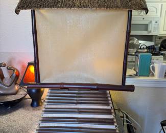 vintage Asian-inspired bamboo and straw-thatched hut accent lamp featuring a warm, illuminated cream-colored shade.
