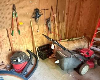 Assorted Garage and Workshop Tools including Walk-Behind Push Lawn Mower, Shop Vacuum, Bolt Cutters, Hand Saw, and Long-Handled Garden Tools