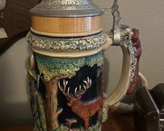 Ornate vintage German lidded beer stein featuring a raised woodland hunting scene, sculpted handle, and decorative pewter lid a striking collectible for stein and hunting enthusiasts! 🍺🦌