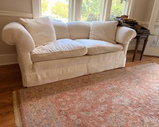 White slipcovered sofa with Oriental area rug