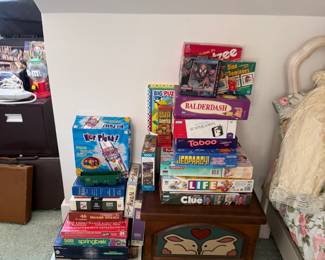 Wicker armchair with plWood desk with monitor and office accessoriesBoard games including Life, Clue and Tabooush dog and children's book