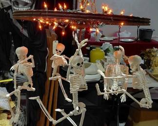 Folk art chandelier made with wooden spoke wheel & posable skeletons