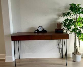 console table, mantle clock, tall plant