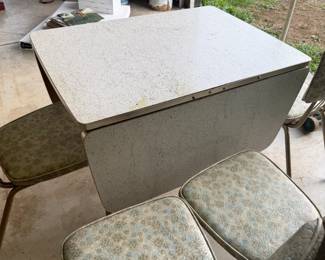 Vintage Formica Drop-Leaf Dining Table with 4 Chairs Vintage dining set featuring a speckled Formica-style tabletop with drop leaves and four matching upholstered chairs. Space-saving table design allows the leaves to fold down when not in use. Chairs feature vintage patterned upholstery with metal frames. Set shows age-related wear consistent with use and storage. Great retro kitchen or dining set. Includes table and all four chairs; see photos for condition.