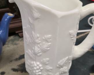 Vintage White Milk Glass Grape & Vine Pitcher Vintage white milk glass pitcher with raised grape and vine pattern, pedestal base and curved handle. Unmarked on bottom. Good vintage condition with light age-related wear; see photos for condition.
