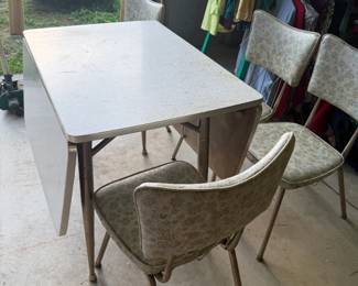 Vintage Formica Drop-Leaf Dining Table with 4 Chairs Vintage dining set featuring a speckled Formica-style tabletop with drop leaves and four matching upholstered chairs. Space-saving table design allows the leaves to fold down when not in use. Chairs feature vintage patterned upholstery with metal frames. Set shows age-related wear consistent with use and storage. Great retro kitchen or dining set. Includes table and all four chairs; see photos for condition.