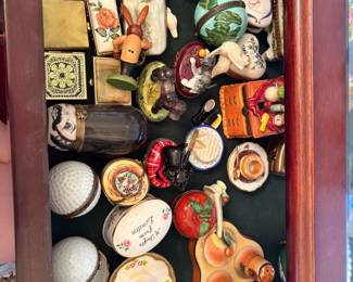 Wide shot of an entire shelf packed with Limoges-style hinged trinket boxes and figural pieces (golf balls, teacups, an apple, a rabbit, a black cat, a chest of drawers, a donut, a croissant plate, an 'A Toffee from London' oval box, plus pieces already priced individually elsewhere in this batch).