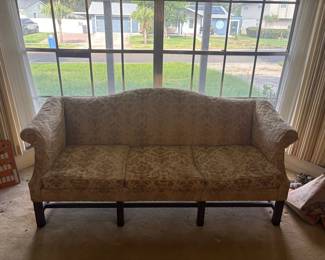 Chippendale-Style Camelback Sofa:  Three-cushion camelback sofa with rolled arms, mahogany straight legs and stretcher base, upholstered in gold/cream damask