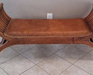 wooden bench with curved, slatted ends and a brown leather upholstered seat