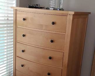  light-wood, five-drawer vertical dresser with a curved front profile and small round knobs