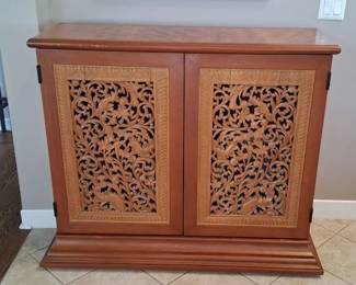 brown wooden accent storage cabinet featuring two doors with intricate, hand-carved botanical floral panels