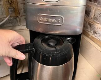 Stainless steel Cuisinart coffee maker has a built-in grinder and a thermal carafe. This unit is a programmable 12-cup model with a brushed metal finish and black accents.